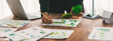 Photo for Businessman planning for green business strategy in office with paper documents focused on eco-friendly and energy sustainable policy to reduce CO2 emission for green environment. Trailblazing - Royalty Free Image