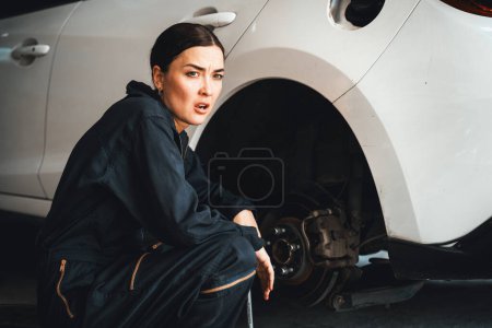 Photo for Hardworking female mechanic changing car wheel in auto repair workshop. Automotive service worker changing leaking rubber tire in concept of professional car care and maintenance. Oxus - Royalty Free Image