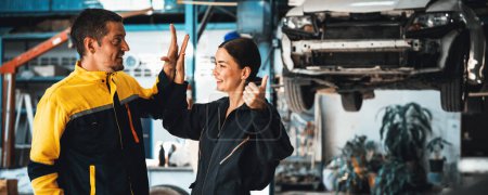 Photo for Two happy vehicle mechanic celebrate and high five after made successful car inspection or repair in automotive service car workshop. Technician team enjoy accomplishment together. Panorama Oxus - Royalty Free Image