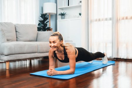 Foto de Mujer mayor atlética y deportiva planking en la alfombra de ejercicio de fitness en el ejercicio en casa como concepto de estilo de vida corporal en forma saludable después de la jubilación. Clout. - Imagen libre de derechos