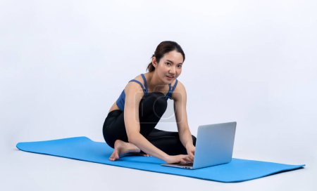 Photo for Young asian woman in sportswear stretching before fitness exercise following instruction from online video. Body workout with healthy athletic woman warming up on isolated background. Vigorous - Royalty Free Image