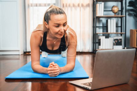 Photo for Athletic and sporty senior woman planking on fitness exercising mat while watching online fitness video at home exercise as concept of healthy fit body lifestyle after retirement. Clout - Royalty Free Image