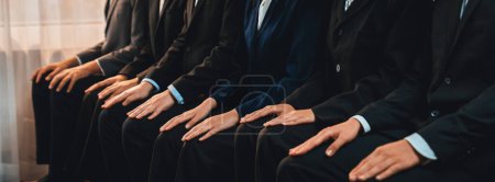 Photo for Asian job applicant waiting in line with good manners hand gesture and identical black formal wear for job interview. Modern and professional job seeker concept. Trailblazing - Royalty Free Image