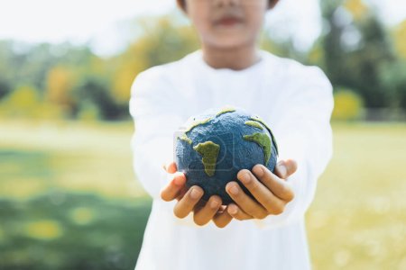 Téléchargez les photos : Jeune garçon asiatique tenant la planète globe terrestre à l'arrière-plan du parc naturel comme jour de la Terre pour sauver cette planète avec le principe ESG et l'énergie respectueuse de l'environnement pour un avenir plus brillant. Pneumatique - en image libre de droit