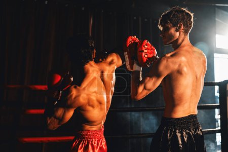 Téléchargez les photos : Le boxeur asiatique et caucasien Muay Thai déclenche une attaque de coude dans une séance d'entraînement de boxe féroce, offrant une frappe de coude à l'entraîneur sparring, mettant en valeur la technique et les compétences de boxe. Impulsion - en image libre de droit