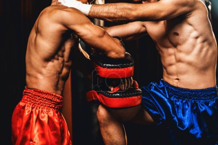 Téléchargez les photos : Le boxeur asiatique et caucasien Muay Thai déclenche une attaque de genou lors d'une séance d'entraînement de boxe féroce, délivrant une frappe de genou à l'entraîneur sparring, mettant en valeur la technique et les compétences de boxe Muay Thai. Impulsion - en image libre de droit