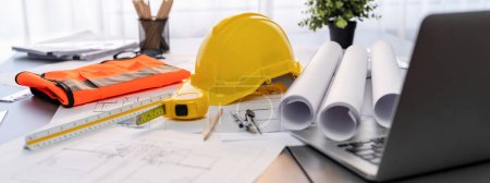 Photo for Architectural designed building blueprint layout and engineer tool for designing blueprint with contractor project document on engineer workspace table in office with safety helmet or hardhat. Insight - Royalty Free Image