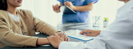 Photo for Doctor show medical diagnosis report and providing compassionate healthcare consultation while holding young patient hand for being supportive and professional in doctor clinic office. Neoteric - Royalty Free Image