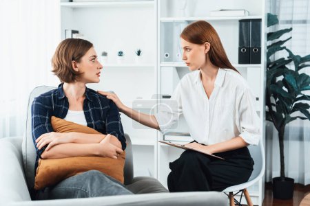 Photo for Sad PTSD woman patient in utmost therapy for mental health with psychologist, depression or grief after life failure. Frustrated trauma young woman talking to a psychologist about emotion in clinic - Royalty Free Image