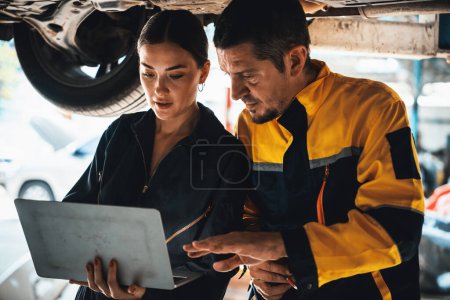 Photo for Two vehicle mechanic working together underneath lifted car, conduct car inspection with laptop. Automotive service technician in uniform carefully make diagnostic troubleshooting. Oxus - Royalty Free Image