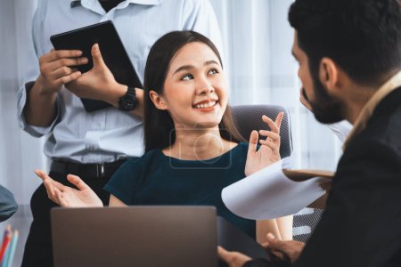Photo for Young Asian businesswoman poses confidently with diverse coworkers in busy meeting room background. Multicultural team works together for business success. Office lady portrait. Concord - Royalty Free Image