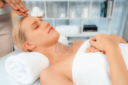 Foto de Mujer caucásica disfrutando de relajante masaje de la cabeza anti-estrés y mimar belleza facial recreación de la piel de ocio en dayspa ambiente de luz moderna en el complejo de lujo o salón de spa del hotel. Silencioso. - Imagen libre de derechos