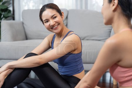 Foto de Mujer asiática en ropa deportiva con su entrenador o compañero de entrenamiento, sonriendo y posando gesto alegre. Entrenamiento en casa entrenamiento o ejercicio estilo de vida fitness en busca de un estilo de vida saludable. Vigoroso - Imagen libre de derechos