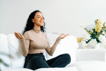 Foto de Mujer afroamericana joven practica meditación consciente crucial en casa sala de estar para mejorar la salud mental fuerza y pacífica hermosa vida - Imagen libre de derechos