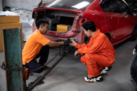 Photo for Mechanic testing strength and reliability of chain hoist for car towing in car workshop garage. Automotive service worker ensure through inspection of mechanical equipment. Oxus - Royalty Free Image