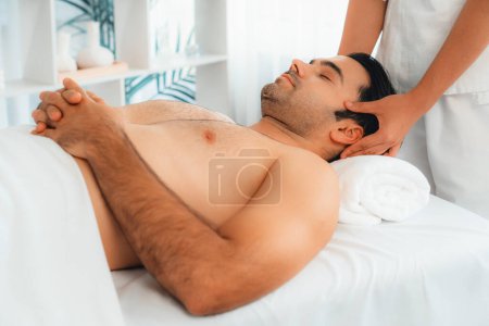 Photo for Caucasian man enjoying relaxing anti-stress head massage and pampering facial beauty skin recreation leisure in dayspa modern light ambient at luxury resort or hotel spa salon. Quiescent - Royalty Free Image