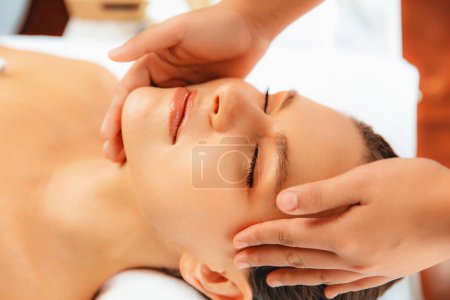 Photo for Closeup woman enjoying relaxing anti-stress head massage and pampering facial beauty skin recreation leisure in dayspa modern light ambient at luxury resort or hotel spa salon. Quiescent - Royalty Free Image