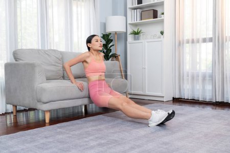 Photo for Energetic and determination asian woman push up on sofa for effective chest targeting muscle gain. Pursuit of fit physique and commitment to healthy lifestyle at home. Vigorous - Royalty Free Image