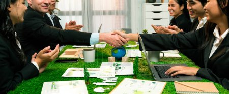 Photo for Handshaking between green business partnership over meeting table after made successful corporate solution to solve global warming with implementation of eco-friendly regulation. Quaint - Royalty Free Image