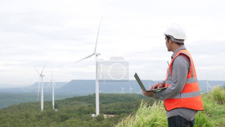 Photo for Engineer working on a wind farm atop a hill or mountain in the rural. Progressive ideal for the future production of renewable, sustainable energy. Energy generation from wind turbine. - Royalty Free Image