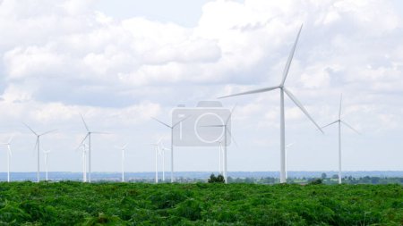 Foto de Manera progresiva de utilizar el viento como fuente de energía renovable para alimentar la forma moderna de vida por el parque eólico en campo verde o colina. Generador de molinos de viento eléctrico sin emisiones de CO2. - Imagen libre de derechos