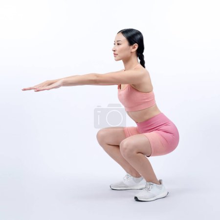 Téléchargez les photos : Femme énergique vigoureuse faisant de l'exercice. Jeune athlète asiatique femme force et endurance séance d'entraînement comme séance de routine d'entraînement squat. Studio complet tourné sur fond isolé. - en image libre de droit