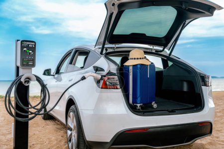 Foto de Viaje por carretera de vacaciones viajando a la playa con batería de recarga de coche eléctrico con energía limpia y ecológica alternativa. Viajes naturales con coche EV para el medio ambiente sostenible. Perpetuo - Imagen libre de derechos