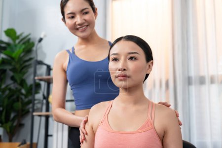 Téléchargez les photos : Femme asiatique en vêtements de sport faire de l'exercice de yoga sur tapis de fitness avec un entraîneur ou un copain d'entraînement comme routine d'entraînement à domicile. Soins du corps sains dans les gens de style de vie yoga. Vigoureux - en image libre de droit