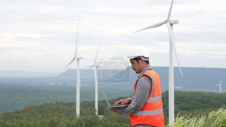 Photo for Engineer working on a wind farm atop a hill or mountain in the rural. Progressive ideal for the future production of renewable, sustainable energy. Energy generation from wind turbine. - Royalty Free Image