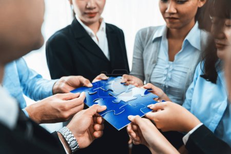 Photo for Multiethnic business people holding jigsaw pieces and merge them together as effective solution solving teamwork, shared vision and common goal combining diverse talent. Meticulous - Royalty Free Image