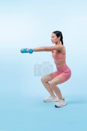 Photo for Vigorous energetic woman doing dumbbell weight lifting exercise on isolated background. Young athletic asian woman strength and endurance training session as body workout routine. - Royalty Free Image
