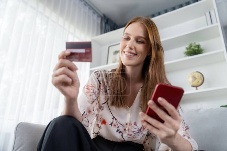 Photo for Young happy woman buy product by online shopping at home while ordering items from the internet with credit card online payment system protected by utmost cyber security from online store platform - Royalty Free Image