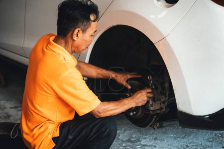 Téléchargez les photos : Mécanicien travailleur changer de roue de voiture dans l'atelier de réparation automobile. Travailleur d'entretien automobile changer les pneus en caoutchouc qui fuient dans le concept d'entretien de voiture professionnelle et d'entretien. Oxus - en image libre de droit