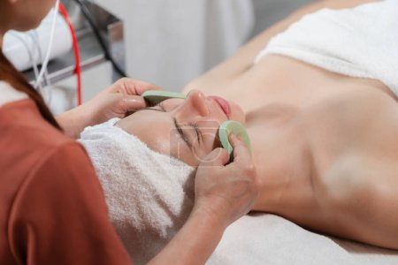 Photo for Beautiful young women lie on spa bed while having facial massage from professional doctor. Attractive female with beautiful skin surrounded by electric facial machine. Tranquility. - Royalty Free Image