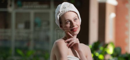 Téléchargez les photos : Portrait de jeune jolie femme caucasienne avec une belle peau en serviette blanche debout en plein air avec confiance entouré par l'environnement naturel. Concept santé et beauté. Gros plan. Tranquillité. - en image libre de droit