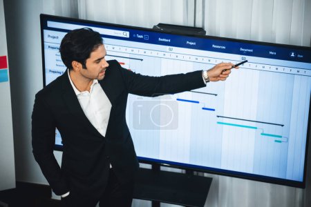 Photo for Project manager planning schedules for business task at meeting room, Gantt chart software show on TV screen. Multi ethnic diversity business people and modern business project management. Meticulous - Royalty Free Image