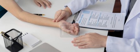 Photo for Patient attend doctors appointment at clinic or hospital office. Doctor discusses medical treatment option, examining and diagnosis symptoms while checking the patients pulse. Panorama Rigid - Royalty Free Image