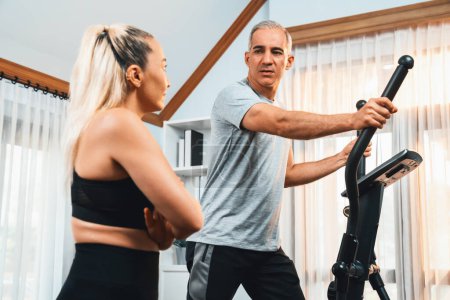 Photo for Active senior couple running on elliptical running machine at home together as fitness healthy lifestyle and body care after retirement for pensioner. Clout - Royalty Free Image