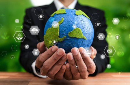 Téléchargez les photos : Un homme d'affaires tenant la Terre avec un design d'icône respectueux de l'environnement symbolise l'engagement de l'entreprise à protéger l'écosystème de la planète Terre avec une technologie zéro net et une pratique ESG. Dépendance - en image libre de droit
