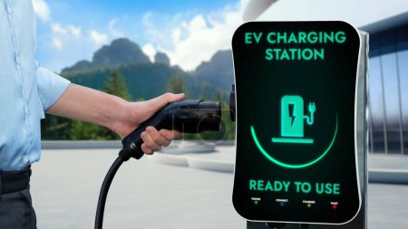 Photo for Businessman holding EV charger from EV charging station with nature background as concept of green future by alternative clean energy technology for environmental awareness. Peruse - Royalty Free Image