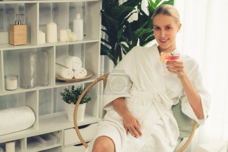 Photo for Beauty or body treatment spa salon vacation lifestyle concept with woman wearing bathrobe relaxing with drinks in luxurious hotel spa or resort room. Vacation and leisure relaxation. Quiescent - Royalty Free Image