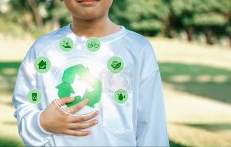 Téléchargez les photos : Symbole de recyclage vert pour la durabilité environnementale et la campagne de sensibilisation à la protection naturelle avec un petit garçon flou promouvant les pratiques ESG recyclables à l'arrière-plan du parc extérieur. Dépendance - en image libre de droit