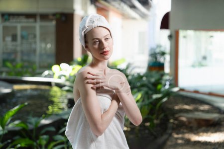 Photo for Attractive Caucasian woman with beautiful skin in white towel standing with confidence surrounded by natural environment at outdoor. Pretty girl standing while waiting for massage. Tranquility. - Royalty Free Image