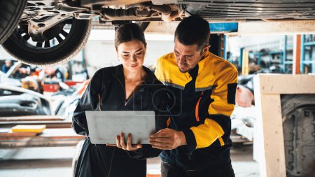 Photo for Two vehicle mechanic working together underneath lifted car, conduct car inspection with laptop. Automotive service technician in uniform carefully make diagnostic troubleshooting. Panorama Oxus - Royalty Free Image