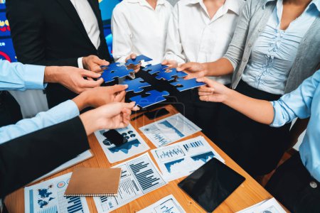 Téléchargez les photos : Des hommes d'affaires multiethniques tenant des pièces de puzzle et les fusionnant en tant que solution efficace pour résoudre le travail d'équipe, la vision partagée et l'objectif commun combinant divers talents. Méticuleux - en image libre de droit