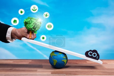 Photo for Businessman balance tree sprout on scale with CO2 emission icon, demonstrate concept of ESG or environment social governance commitment to carbon reduction through clean energy technology. Reliance - Royalty Free Image