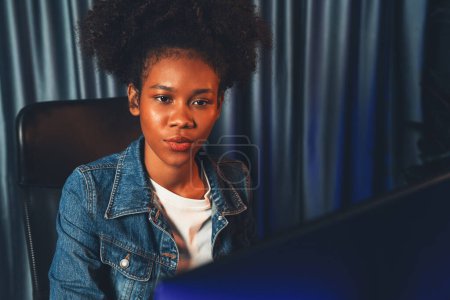 Photo for Young African American woman with surprise face, wearing blue jeans shirt and looking at final project document on laptop for planing next sequence. Concept of work at neat home place. Tastemaker. - Royalty Free Image