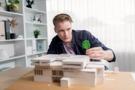 Photo for Architect designer studies elegant house model, reviewing structure design for improvement with construction plan on table. Creativity and innovation in architectural design. Iteration - Royalty Free Image