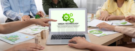 Foto de Logotipo de tecnología verde se muestra en el ordenador portátil de negocios verde, mientras que el equipo de negocios presenta diseño verde al cliente. ESG medio ambiente gobernanza social y Eco concepto conservador. Primer plano. Delineación - Imagen libre de derechos