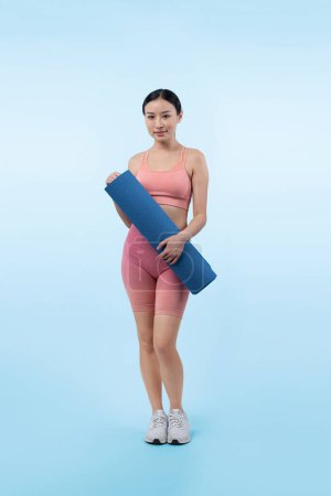 Téléchargez les photos : Jeune femme asiatique attrayant portrait en vêtements de sport avec tapis d'exercice. Exercice sain et routine d'entraînement concept de mode de vie. Studio a tourné en arrière-plan isolé. Vigoureux - en image libre de droit